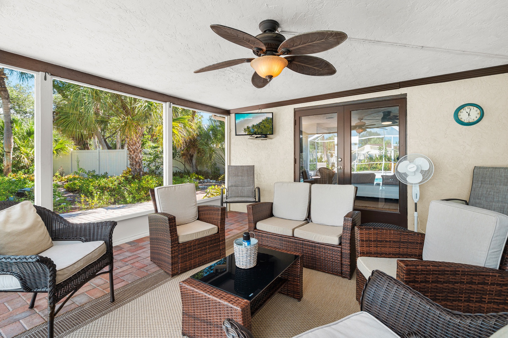Settle into your private screened-in patio with tropical garden views, where comfortable rattan seating and a gentle ceiling fan create the perfect retreat for morning coffee or evening relaxation.