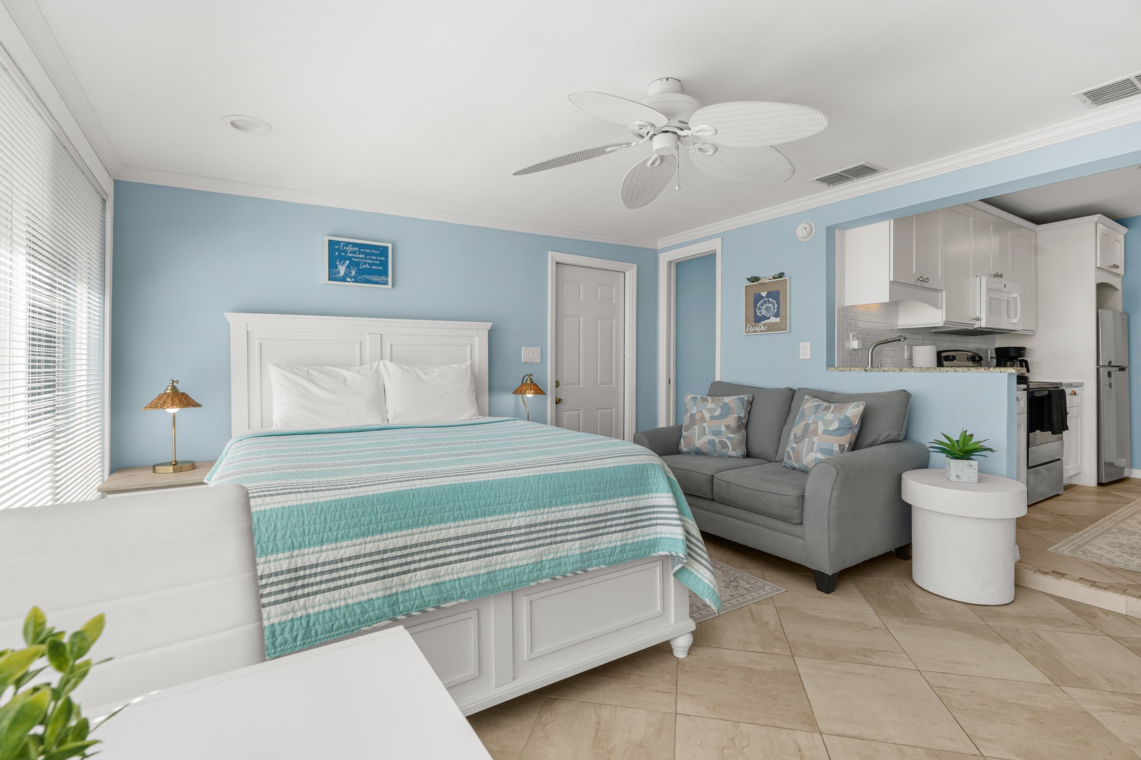 Relax in your bright, coastal-styled studio with soothing blue walls, comfortable bed, and fully equipped kitchen for your perfect getaway.