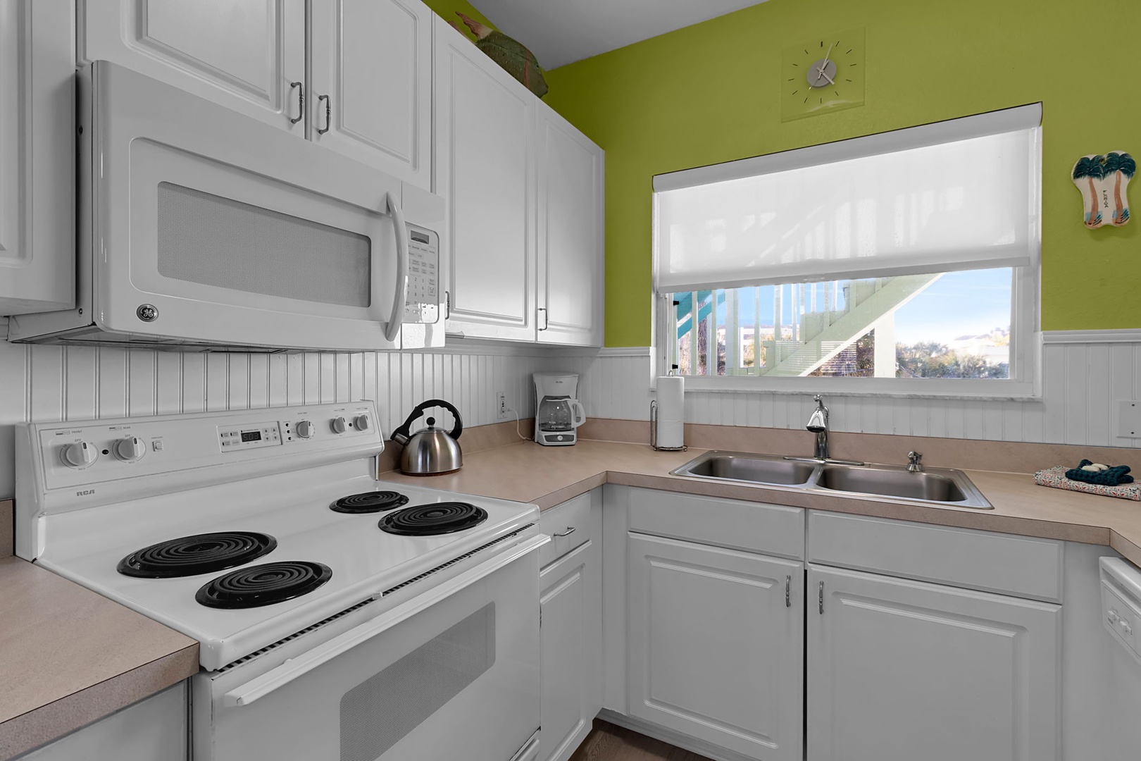 Your fully equipped kitchen features bright white cabinetry, modern appliances, and a cheerful lime accent wall, making meal prep feel fresh and inviting.