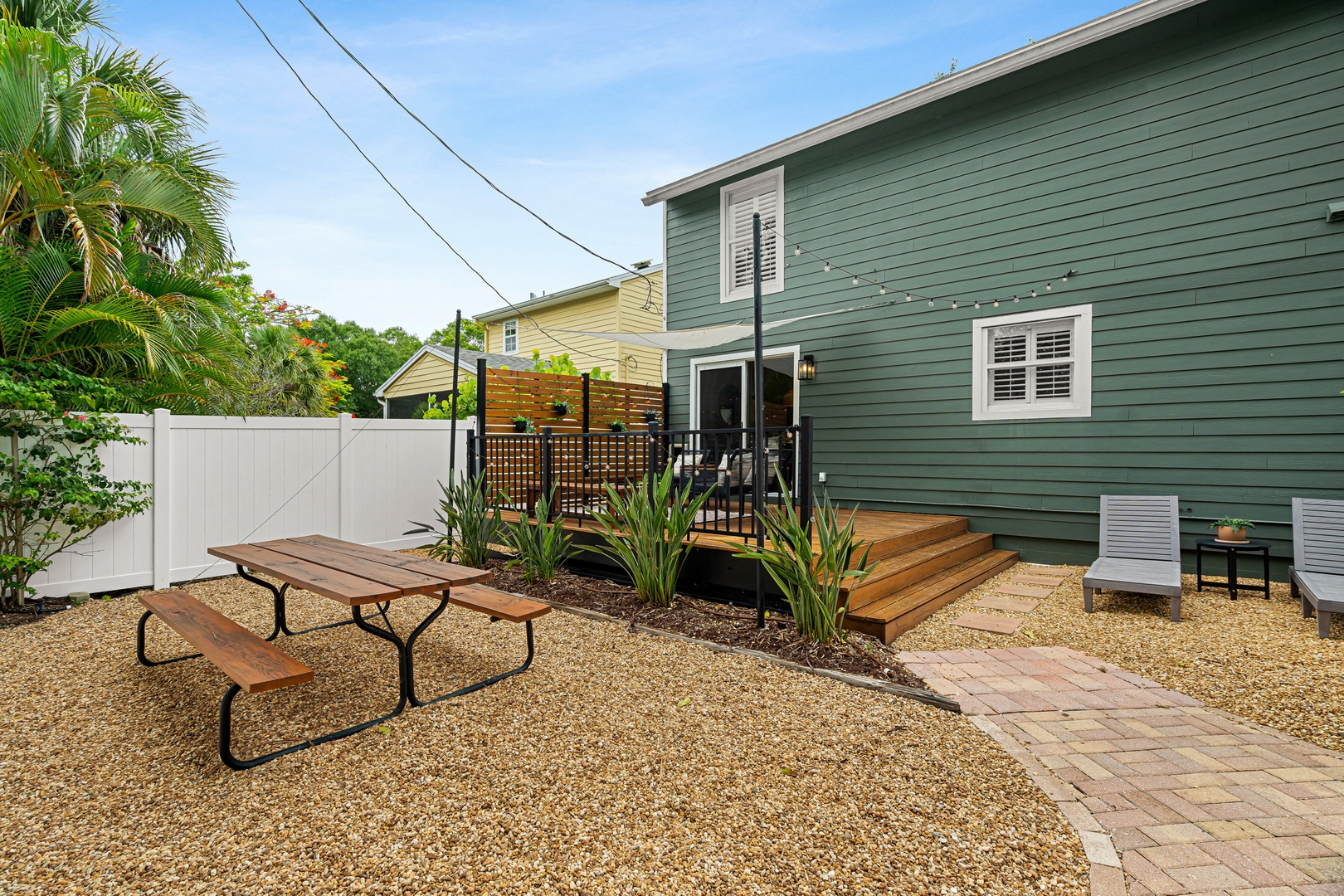 Coastal-inspired property featuring a private outdoor space with picnic table, deck access, and tropical greenery—perfect for morning coffee or sunset gatherings.