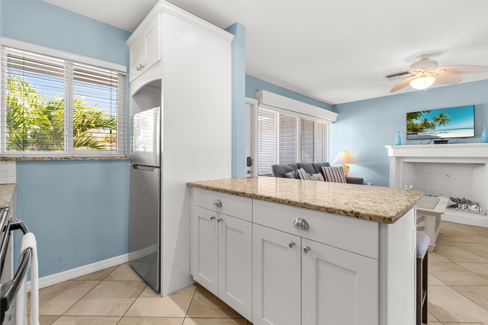 Your bright kitchen features granite counters, white cabinetry, and stainless appliances with tropical views.