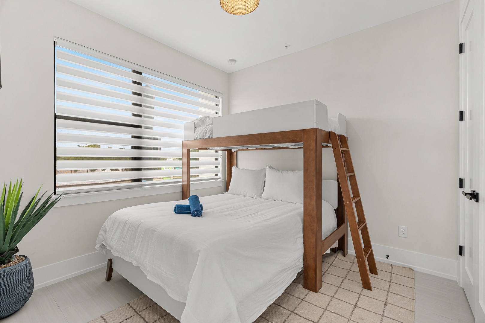 Your bright, peaceful bedroom features fresh linens and a warm woven ceiling light that adds a cozy coastal touch. Perfect for families or groups, with space to spread out and settle in.