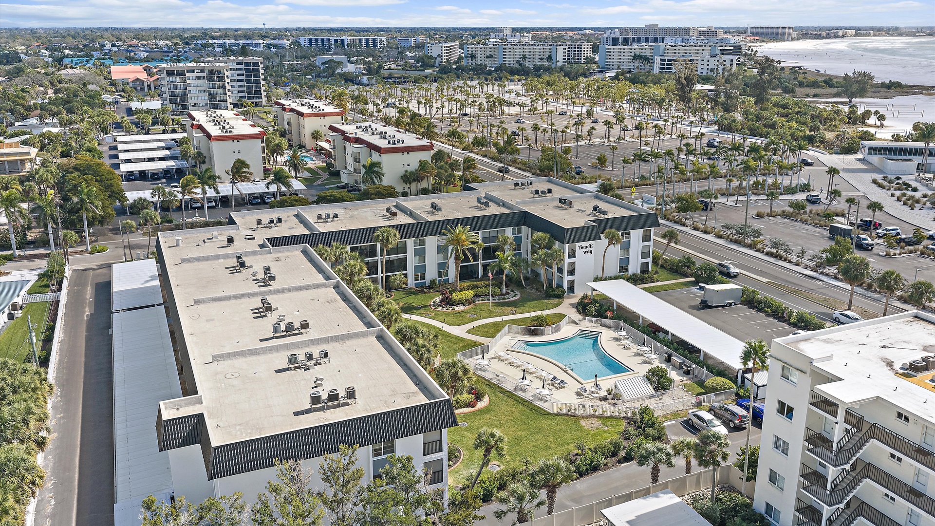 Aerial view of the modern resort complex with tropical landscaping, central swimming pool, and well-appointed accommodations.