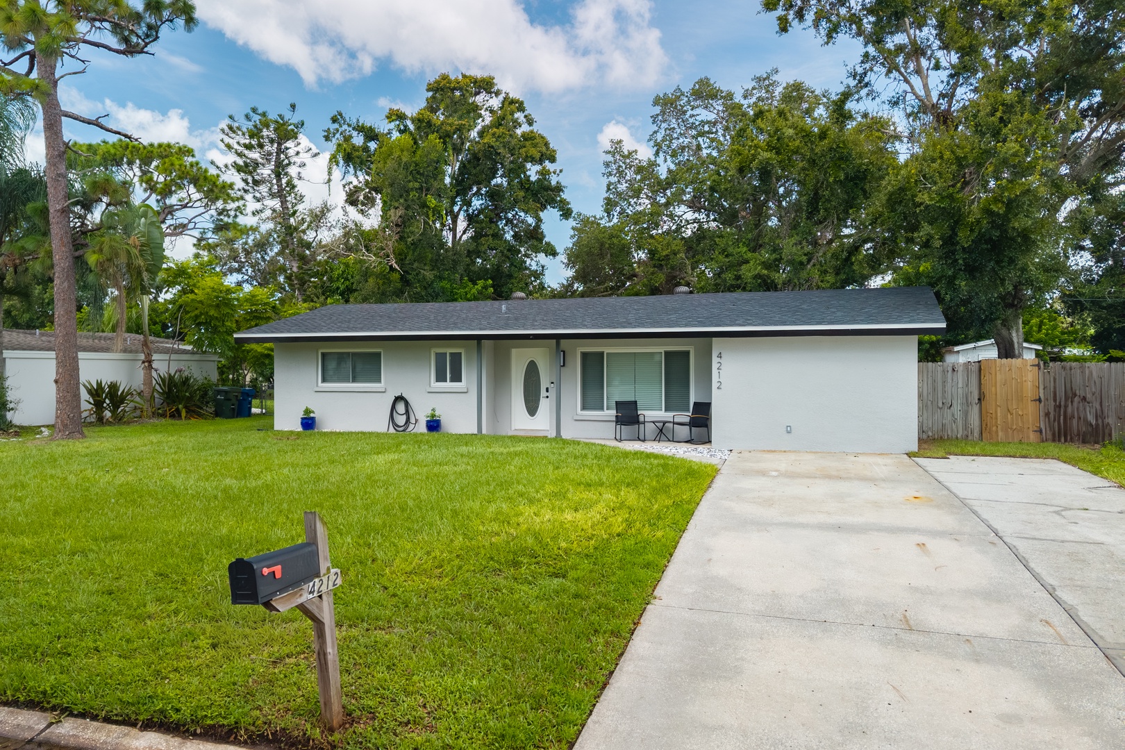 Charming single-story home nestled among mature trees with convenient driveway parking and peaceful neighborhood setting.