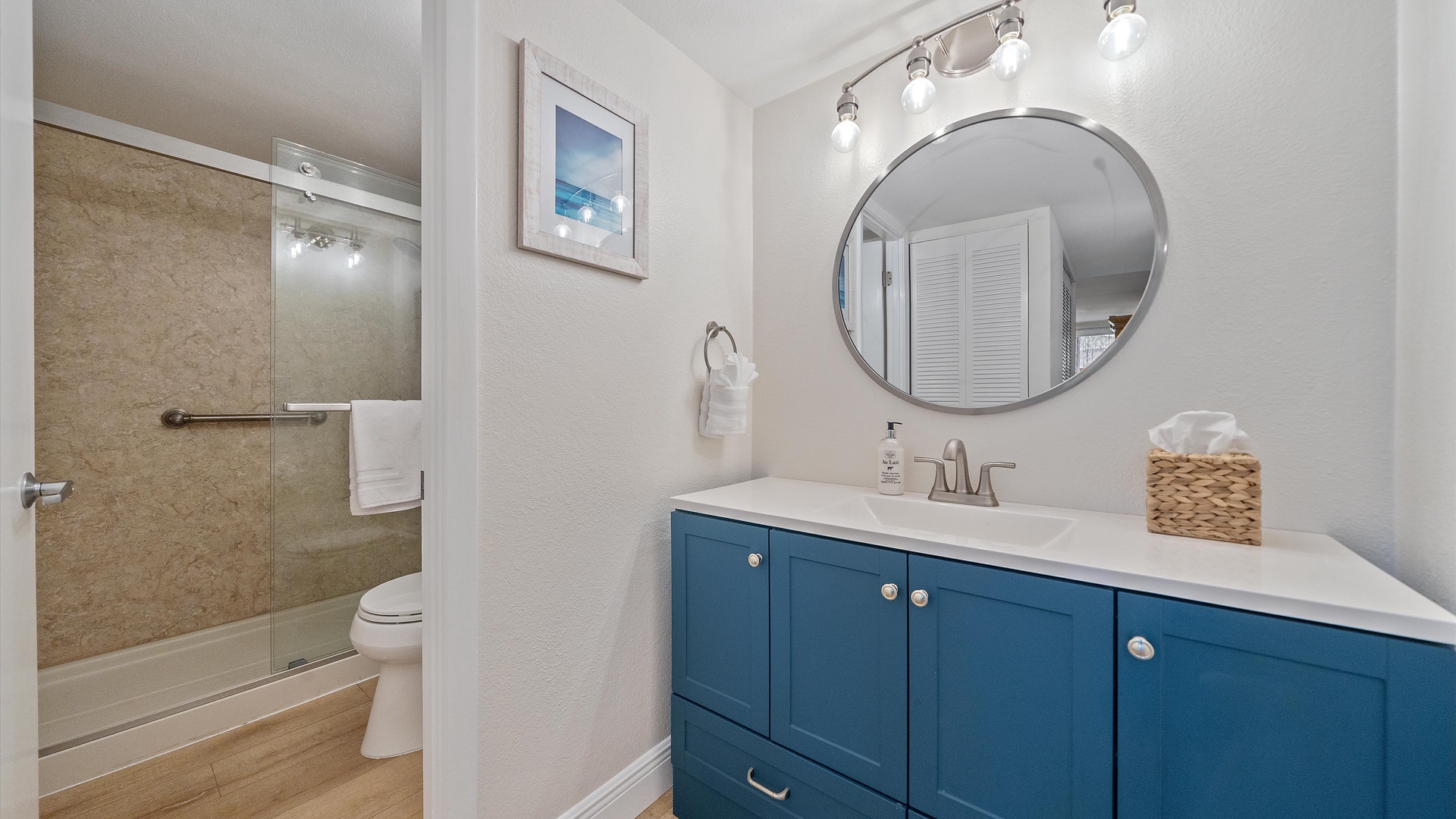Refresh in your beautifully appointed bathroom with coastal blue cabinetry, modern fixtures, and a glass-enclosed shower for your daily routine.