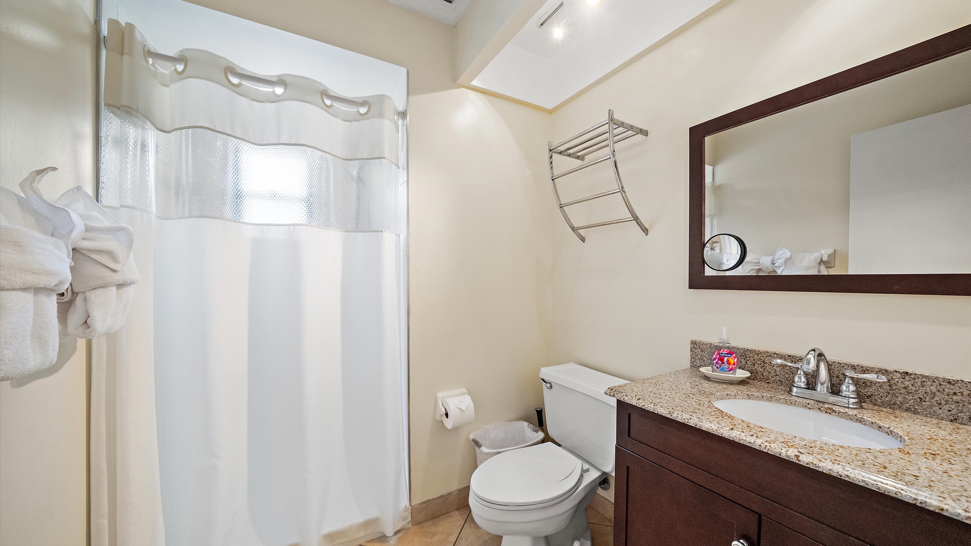 Refresh in your private bathroom featuring a spacious walk-in shower, granite vanity, and thoughtful touches like fresh towels and a lighted mirror for your comfort.