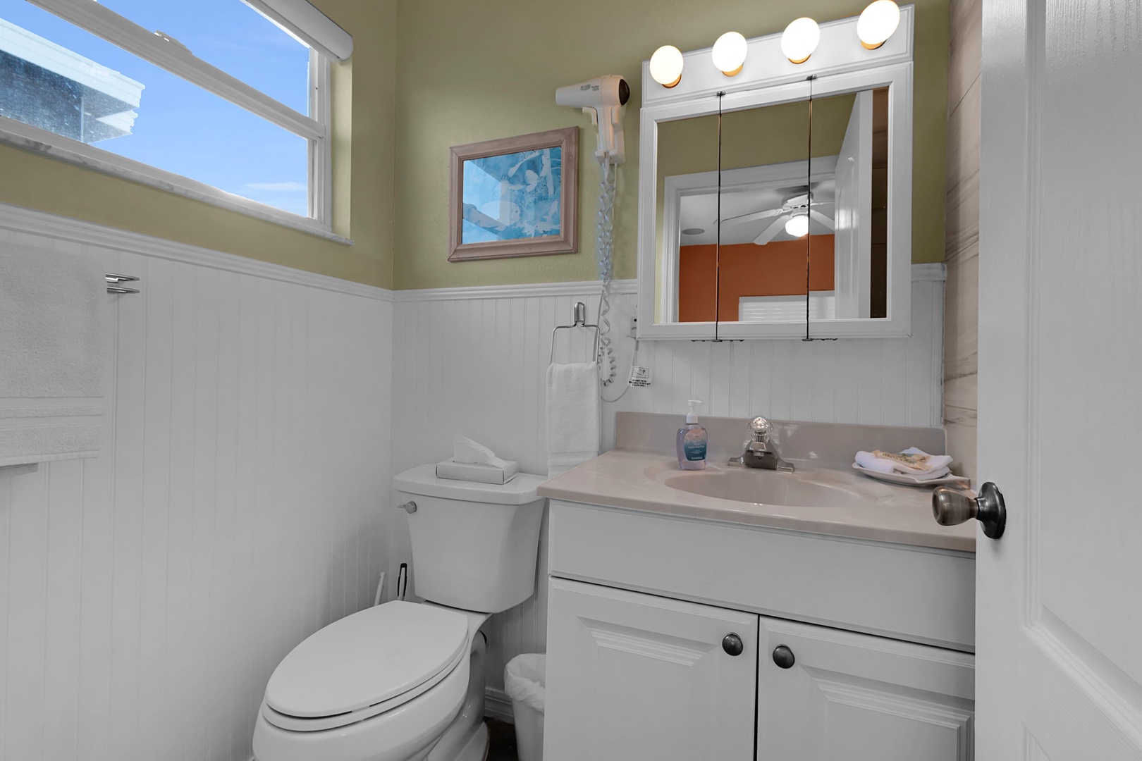 Step into your bright, spotless bathroom with fresh white beadboard, a well-lit vanity, and a convenient handheld shower. Natural daylight streams in, making your morning routine feel effortless.