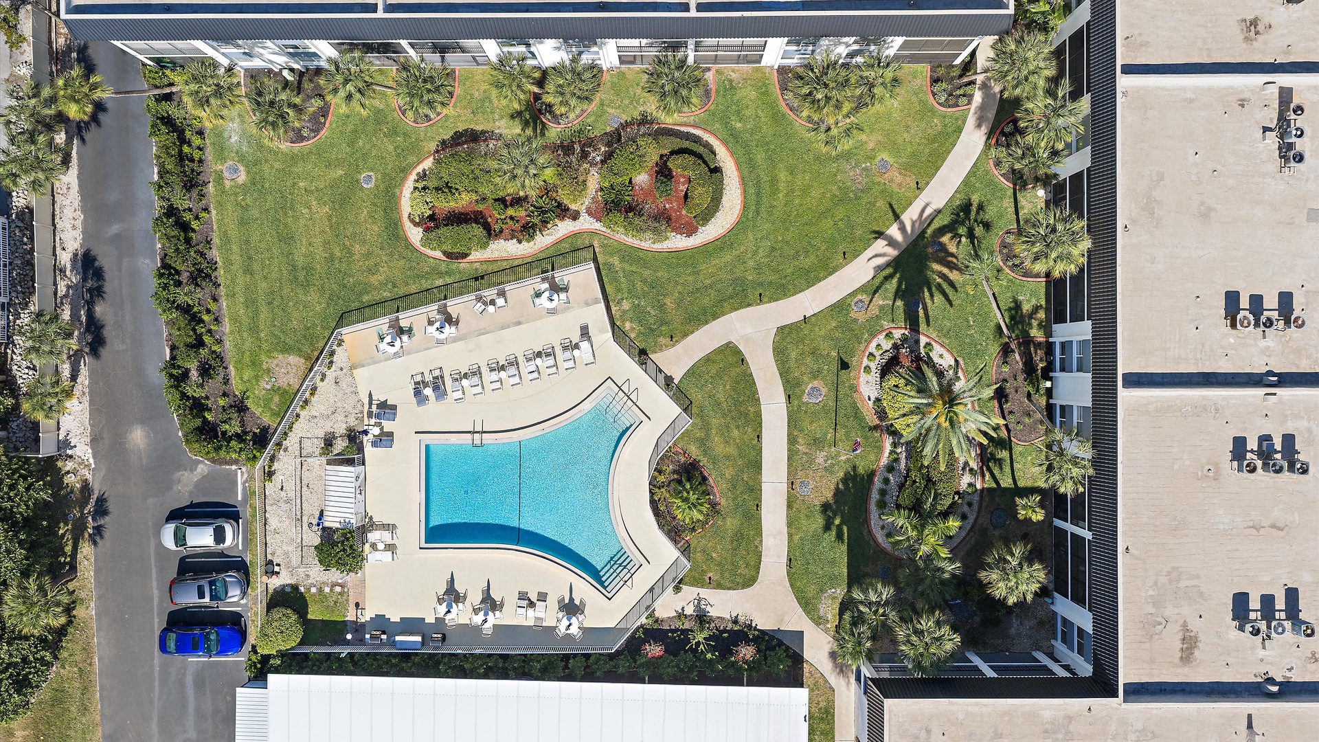 Tropical resort complex with curved swimming pool, lush gardens, and palm trees throughout the landscaped grounds.