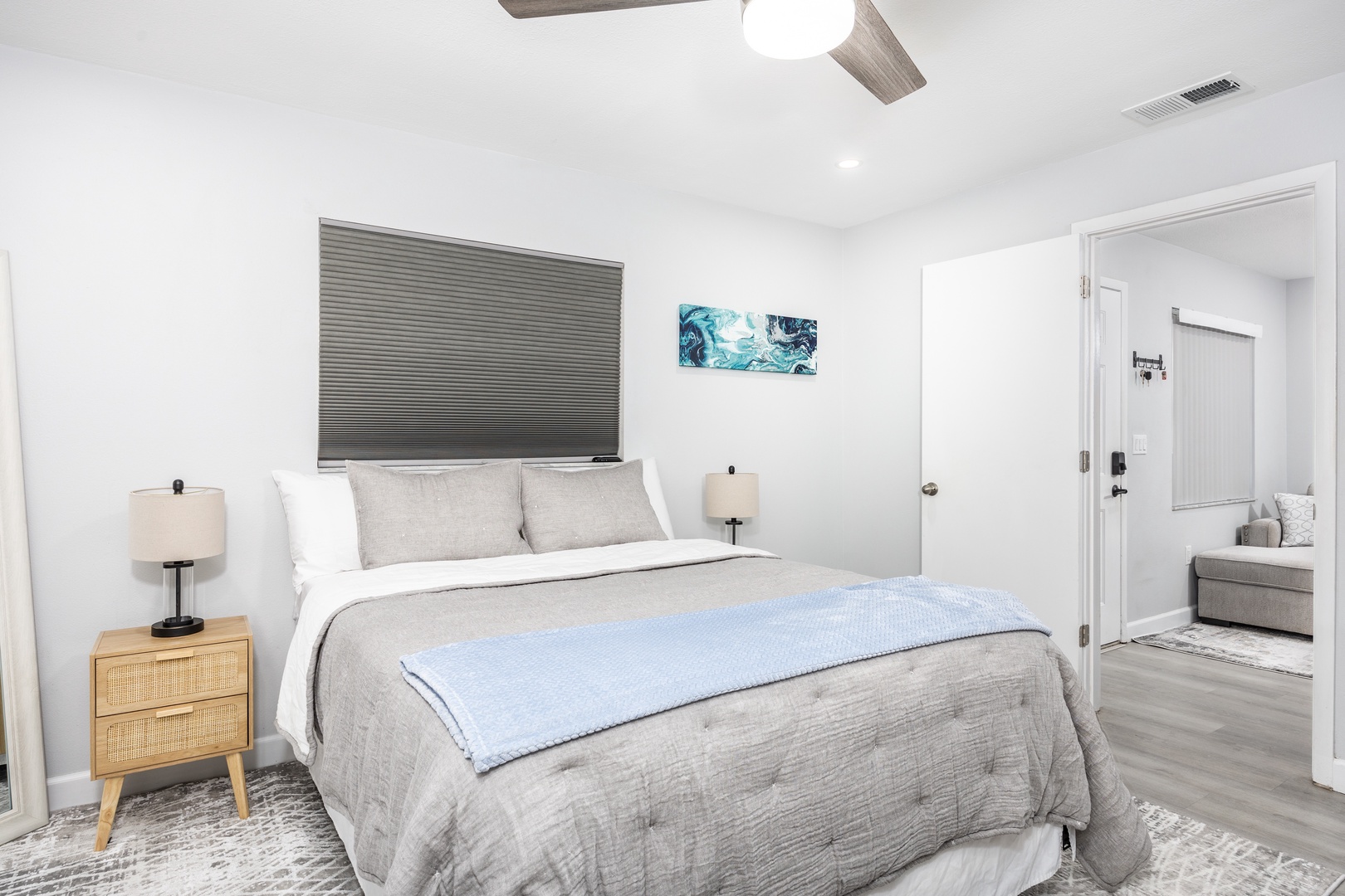 Sink into this serene bedroom's plush bedding and modern coastal vibes. Your restful retreat awaits with stylish furnishings and tranquil blue accents.