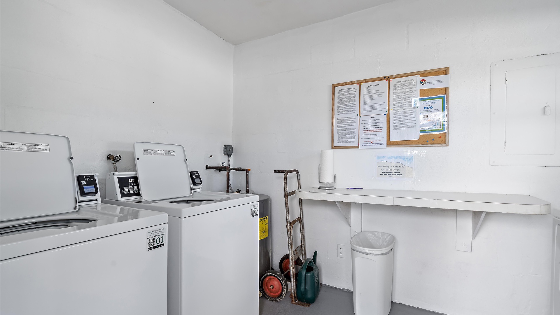 Keep your wardrobe fresh in this well-equipped laundry room with modern washers, dryers, and a convenient folding counter for your convenience.