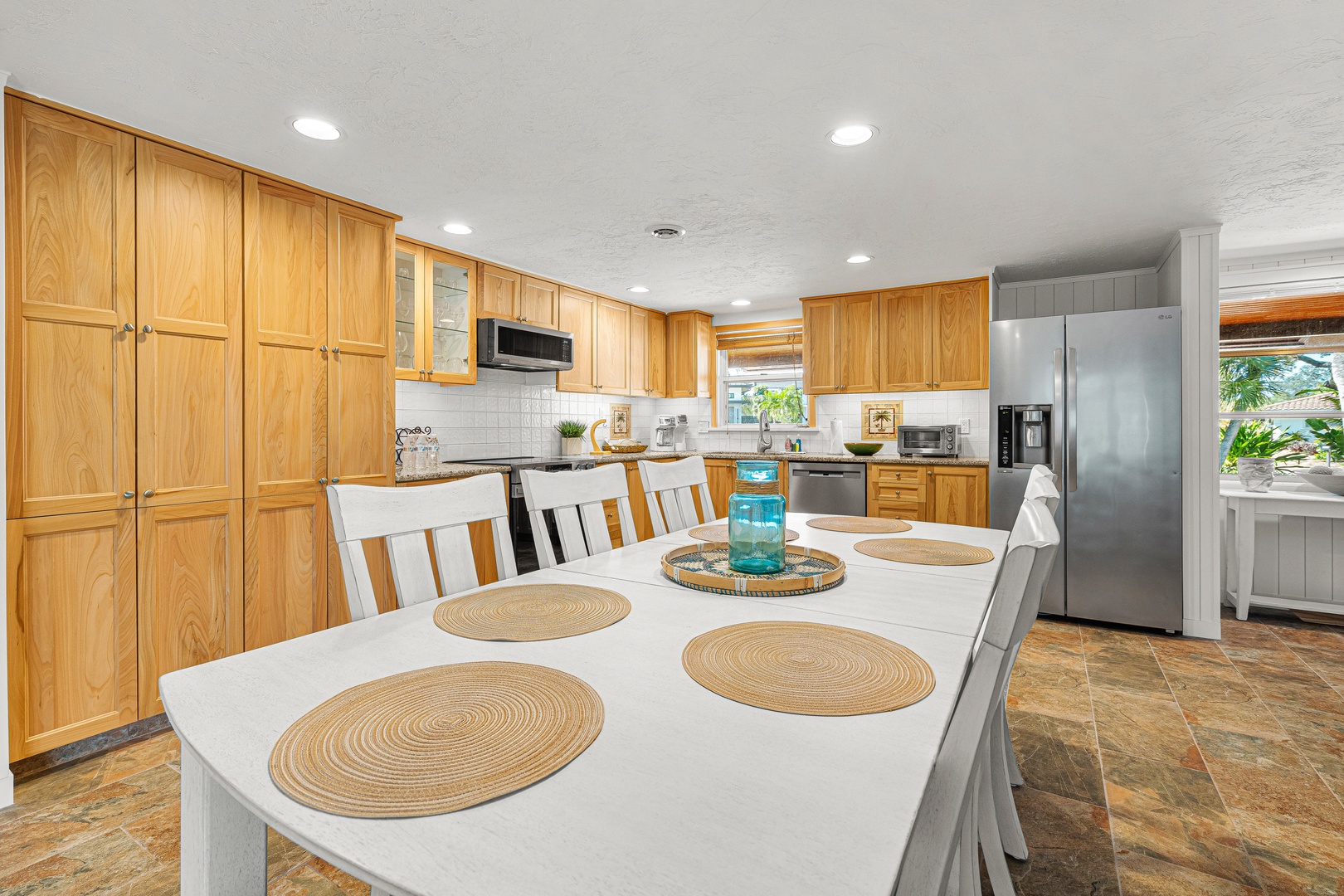 Gather around this generous dining table in your fully-equipped kitchen with warm wood cabinetry and modern appliances—the perfect blend of comfort and convenience.
