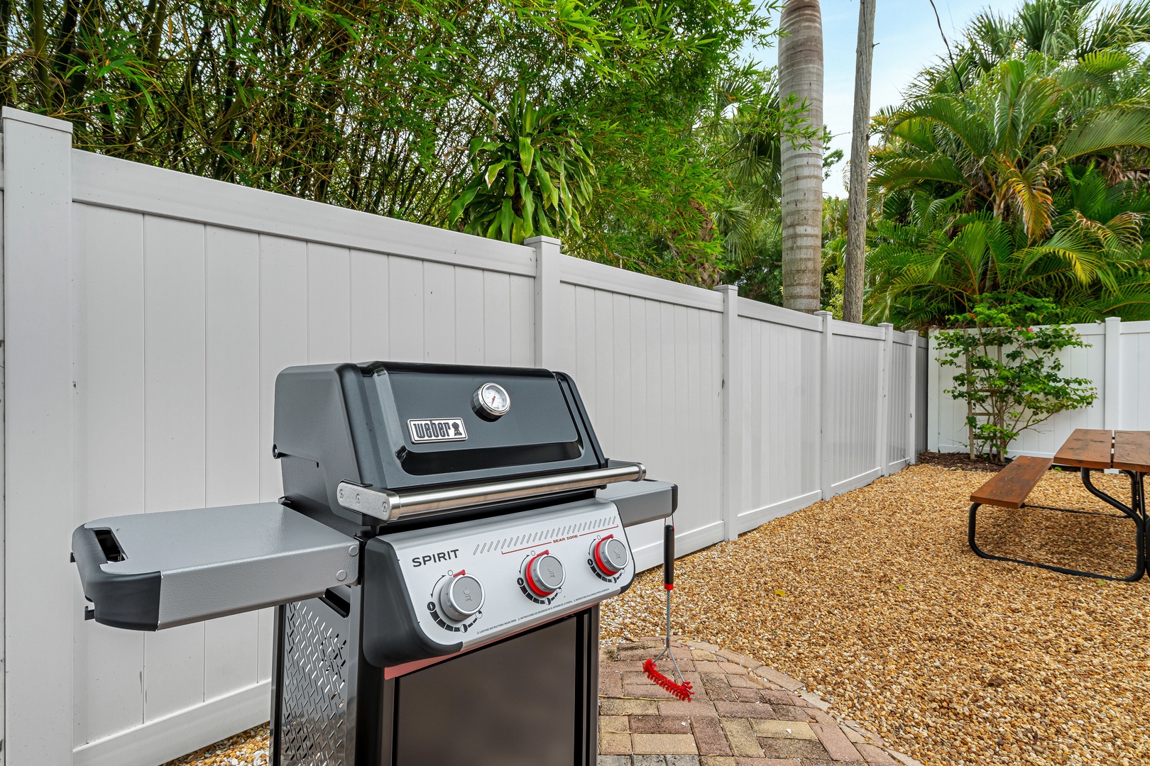 Your private outdoor space features a Weber Spirit grill surrounded by lush tropical greenery, perfect for sizzling up meals al fresco under swaying palms.