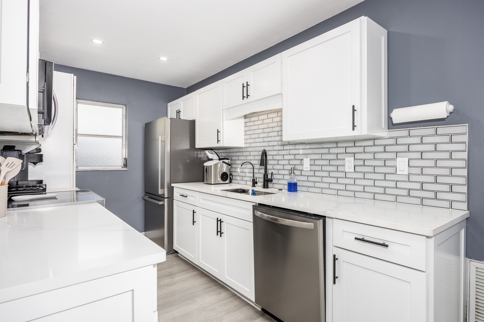 Your fully equipped kitchen features sleek white cabinets, stainless steel appliances, and stylish subway tile backsplash for all your culinary adventures.