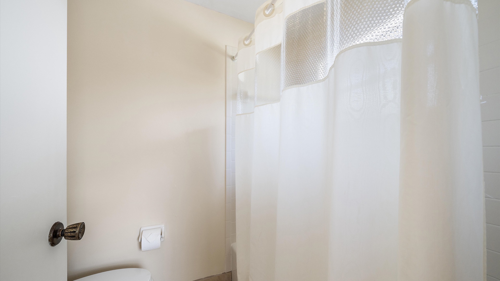 A crisp white shower curtain awaits, ready for your refreshing morning or evening rinse in this clean, comfortable bathroom space.