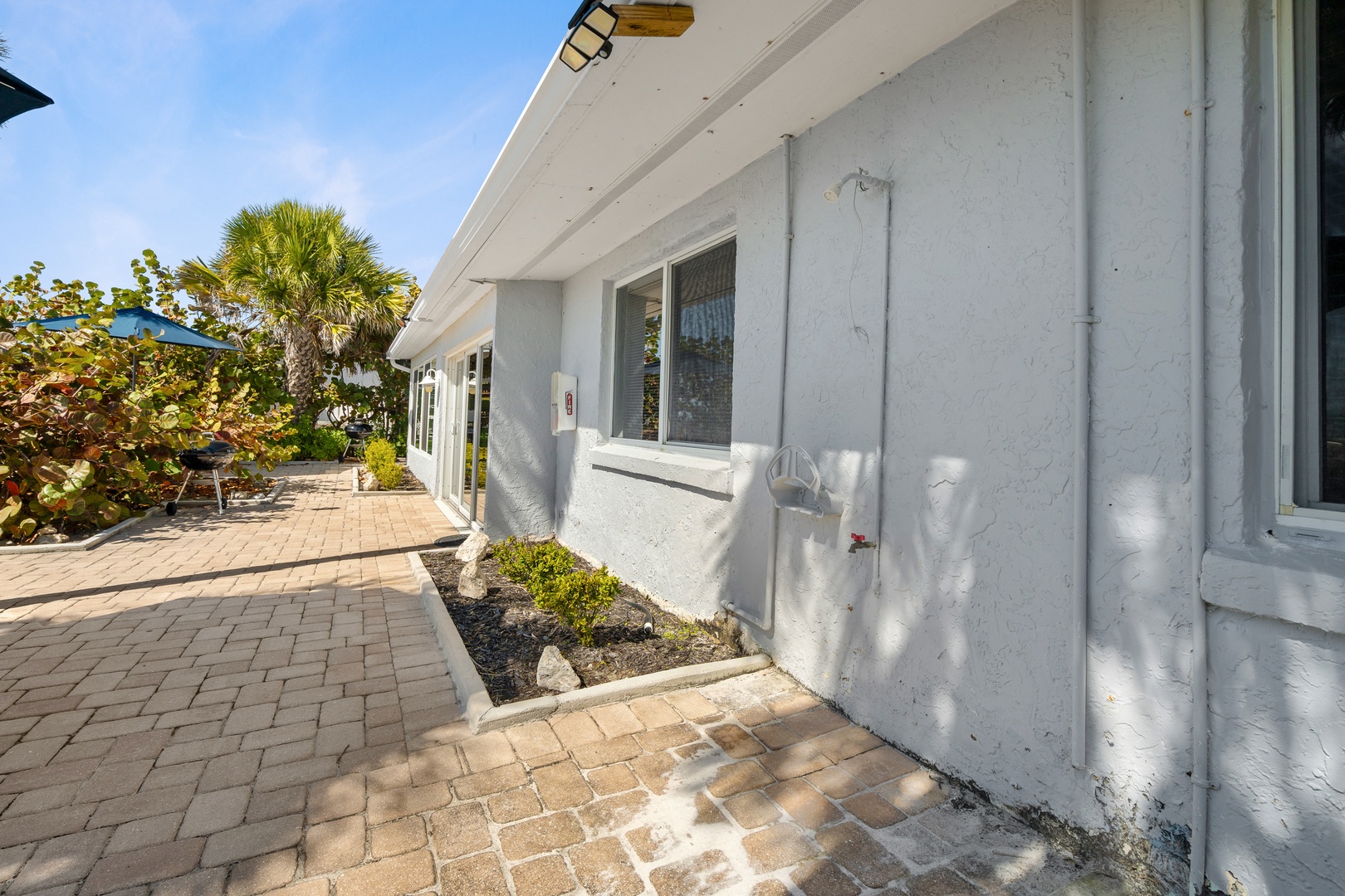 Clean white exterior with paved walkways and tropical landscaping creates a welcoming arrival experience.