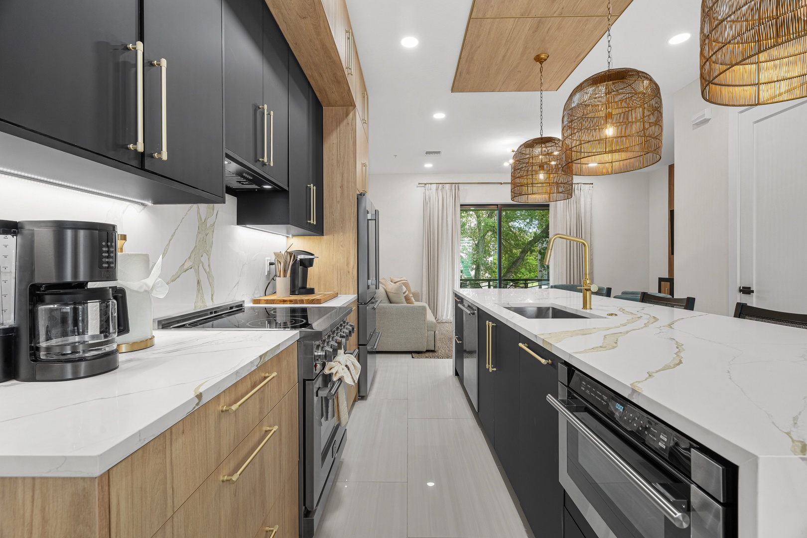 Your beautifully designed kitchen blends sleek modern style with natural warmth, featuring marble countertops, gold fixtures, statement woven pendant lights, and everything you need to create memorable meals together.