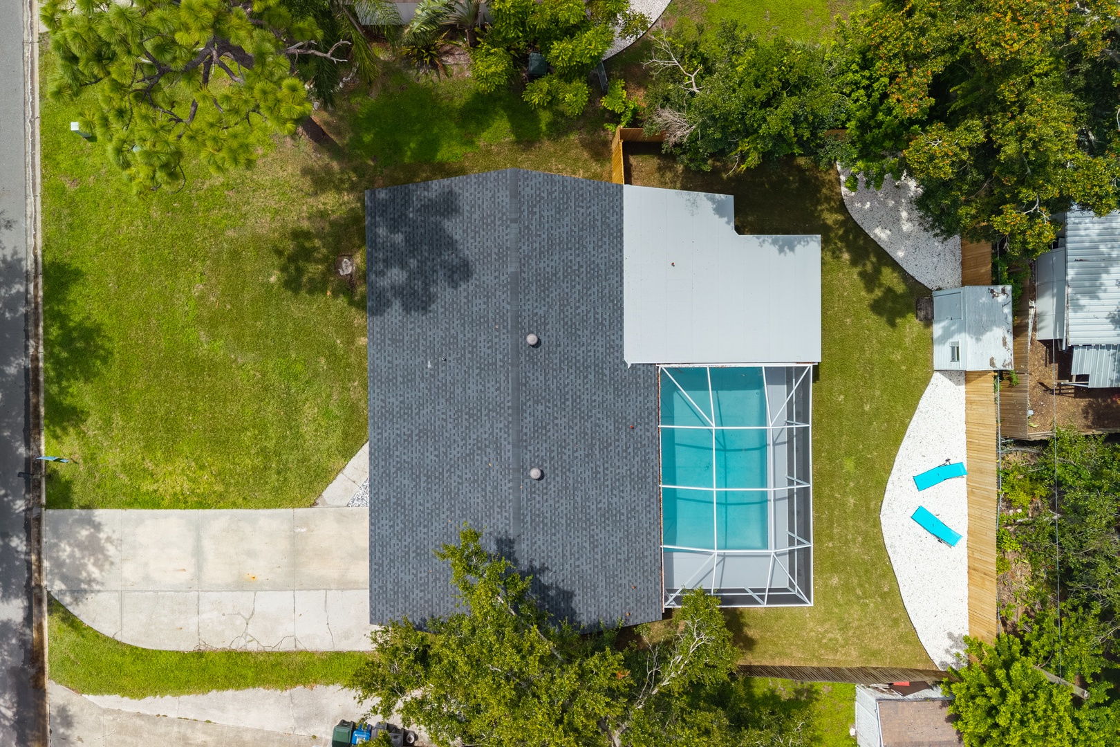 Aerial view of vacation rental property featuring a modern home with swimming pool nestled among lush green landscaping and mature trees.