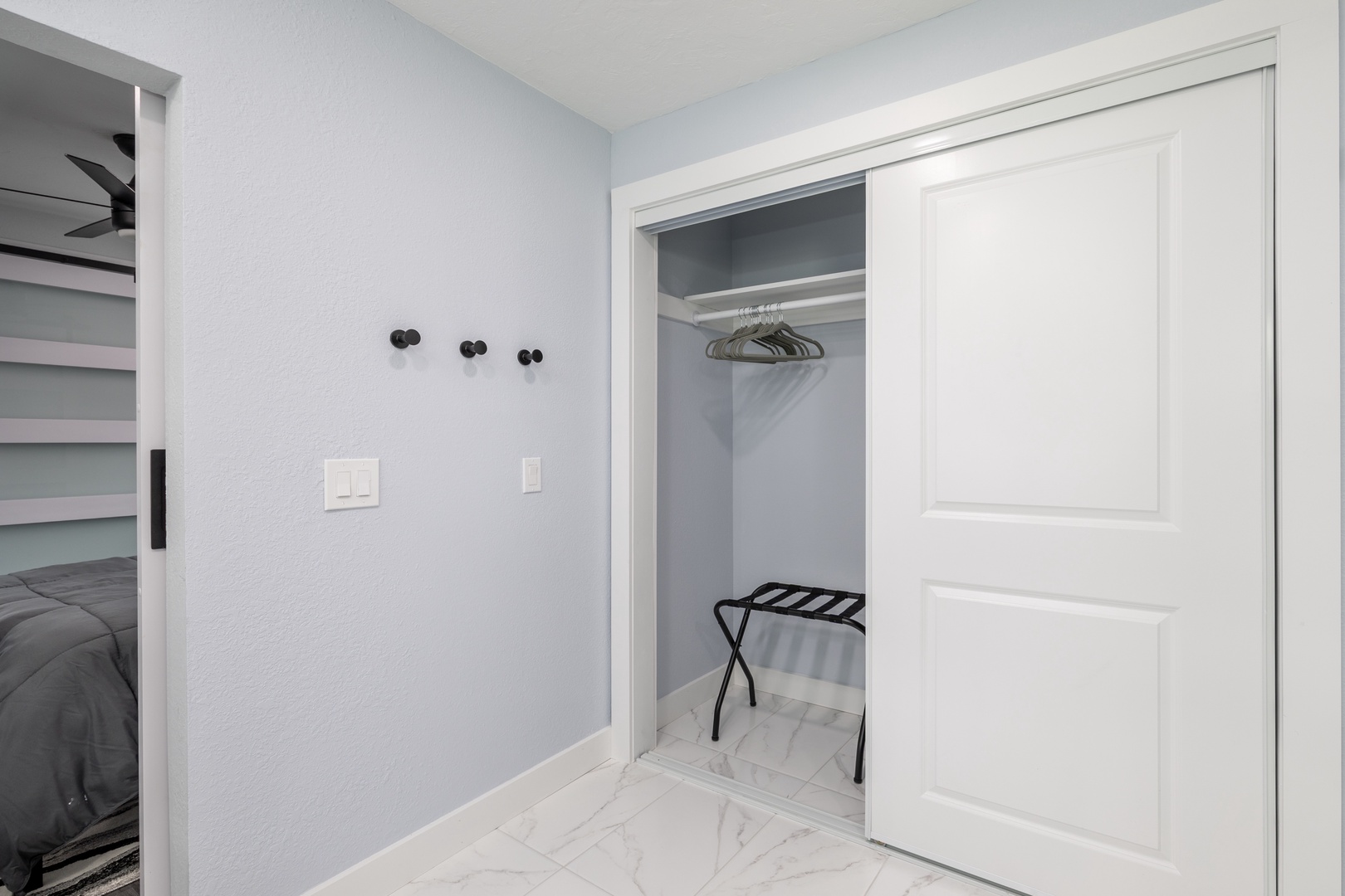 Your spacious walk-in closet offers ample hanging space and thoughtful touches like convenient wall hooks and a luggage rack for unpacking.