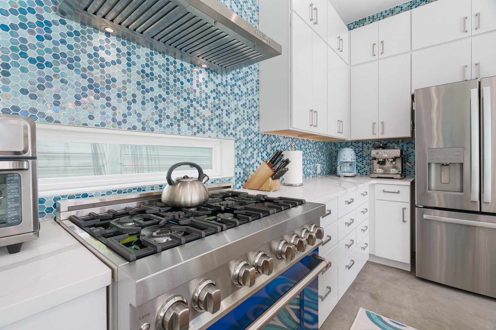 Step into your beautifully appointed kitchen, featuring stunning turquoise mosaic tilework, stainless steel appliances, and everything you need to whip up memorable meals during your stay.