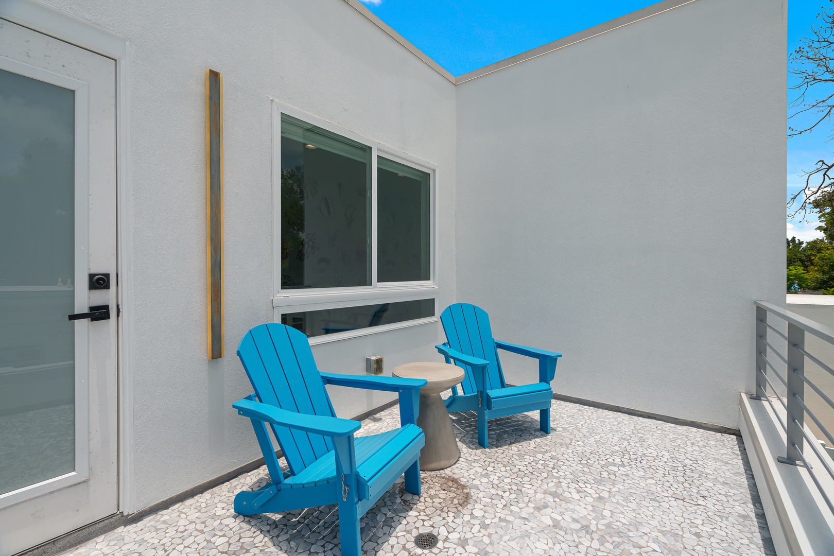 Modern private terrace featuring bright blue Adirondack chairs and contemporary clean lines perfect for morning coffee or evening relaxation under open skies.