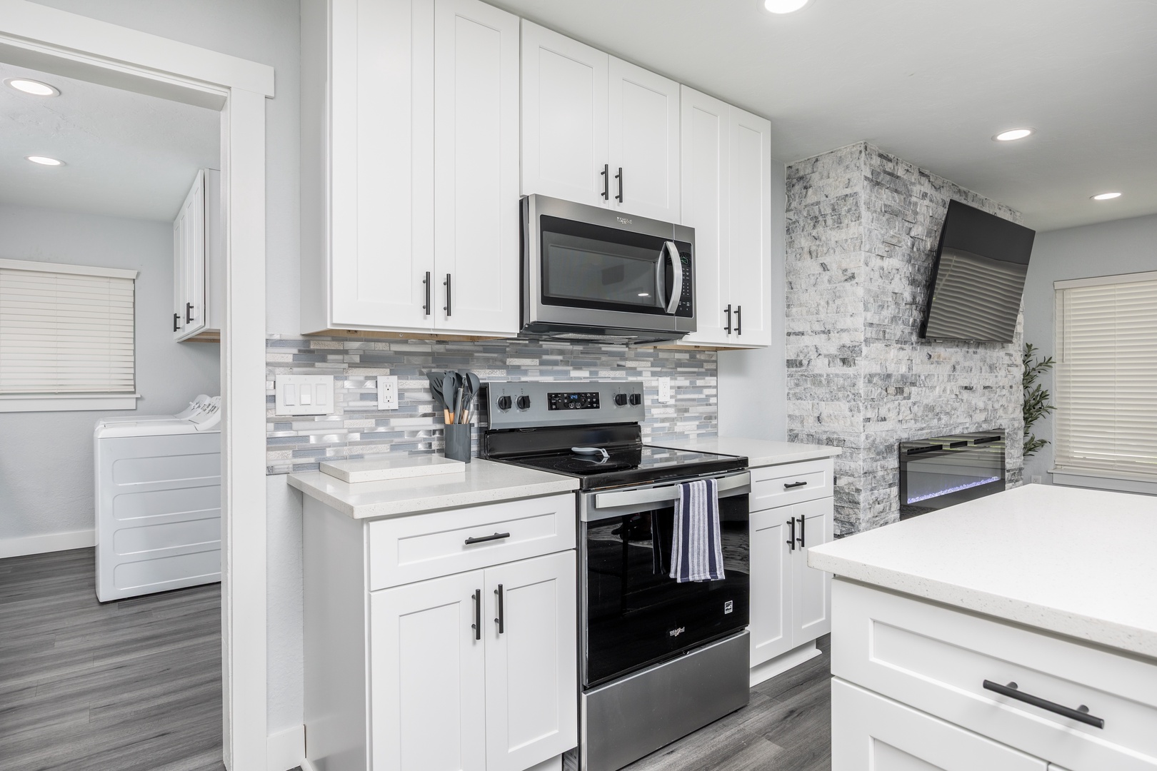 Your modern kitchen features sleek white cabinets, stainless appliances, and stunning stone backsplash—perfect for creating memorable meals together.