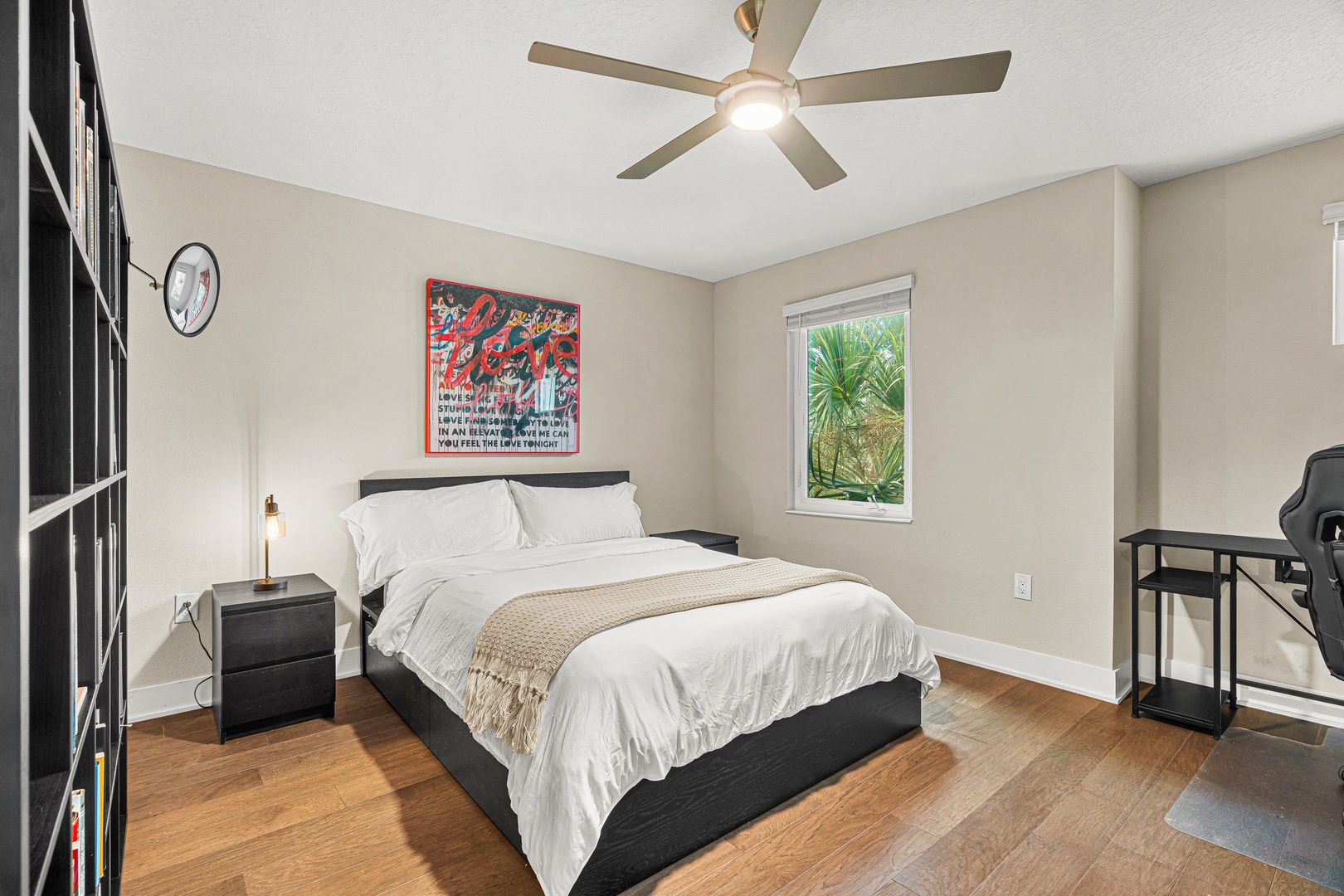 Sink into crisp white linens and let the ceiling fan's gentle breeze ease you into relaxation. With tropical greenery framed outside your window, this is your peaceful retreat.