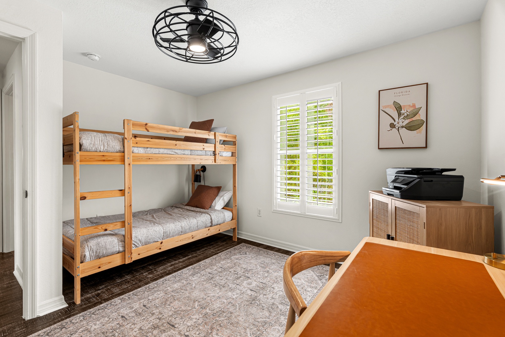 This cozy bedroom features warm wood bunk beds and natural light streaming through plantation shutters, creating a comfortable retreat for your group or family during your stay.