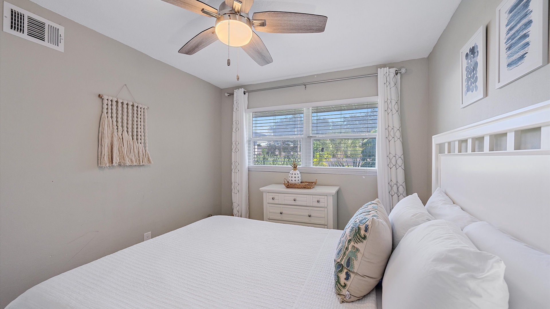 Drift off under the soft glow of the ceiling fan in your peaceful bedroom, where natural light and coastal-inspired touches create your perfect escape.