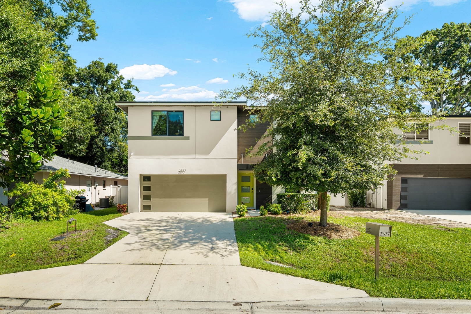 A modern two-story home set in a lush, tree-lined neighborhood with clean architectural lines, an inviting front entry, and convenient garage parking awaits your arrival.