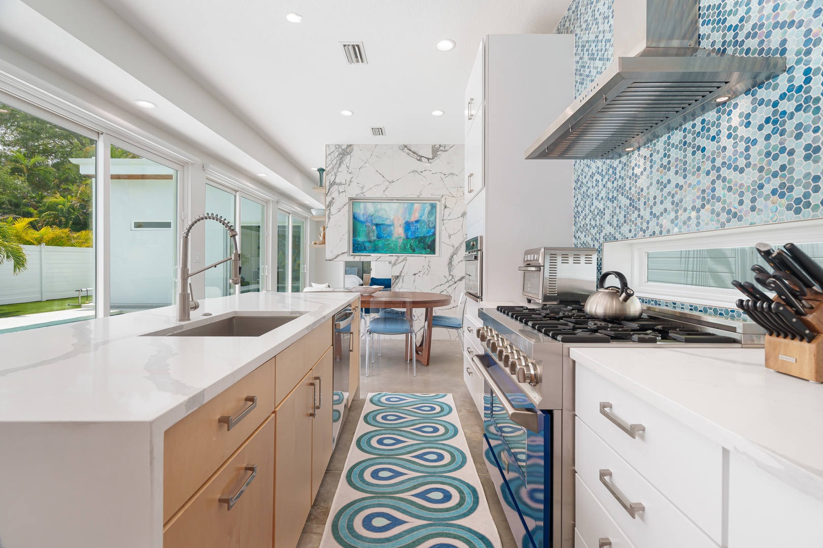 Cook in this sleek modern kitchen with stunning marble accents, mosaic backsplash, and a pro-grade gas range that opens to your own private outdoor oasis.