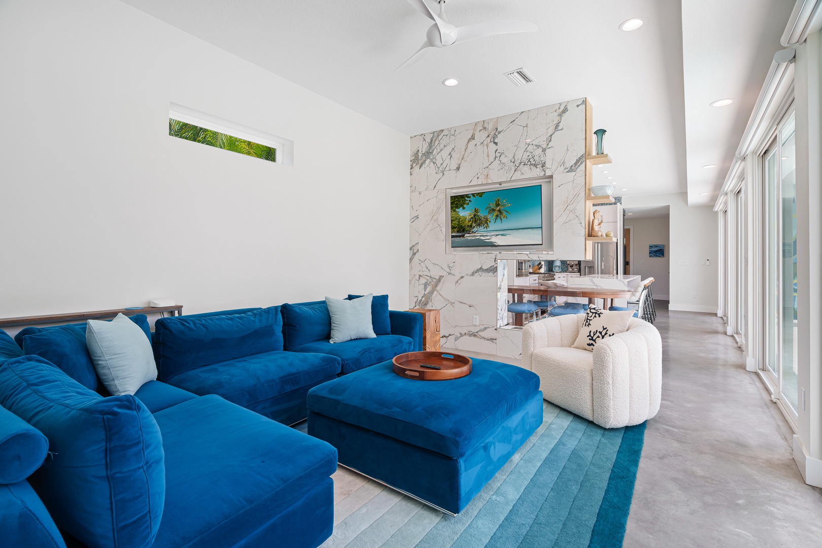 Enjoy the plush living room area with Smart TV and fireplace, floor to ceiling sliders that open up to the pool area.