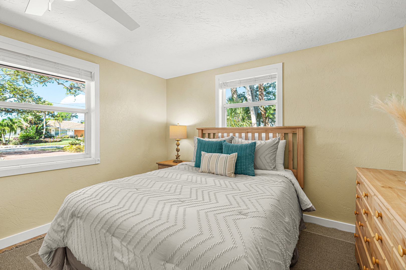 Drift off in your cozy retreat, where soft linens and cheerful pops of teal welcome you after a day of adventure. Natural light fills the space through bright windows, creating a peaceful escape.