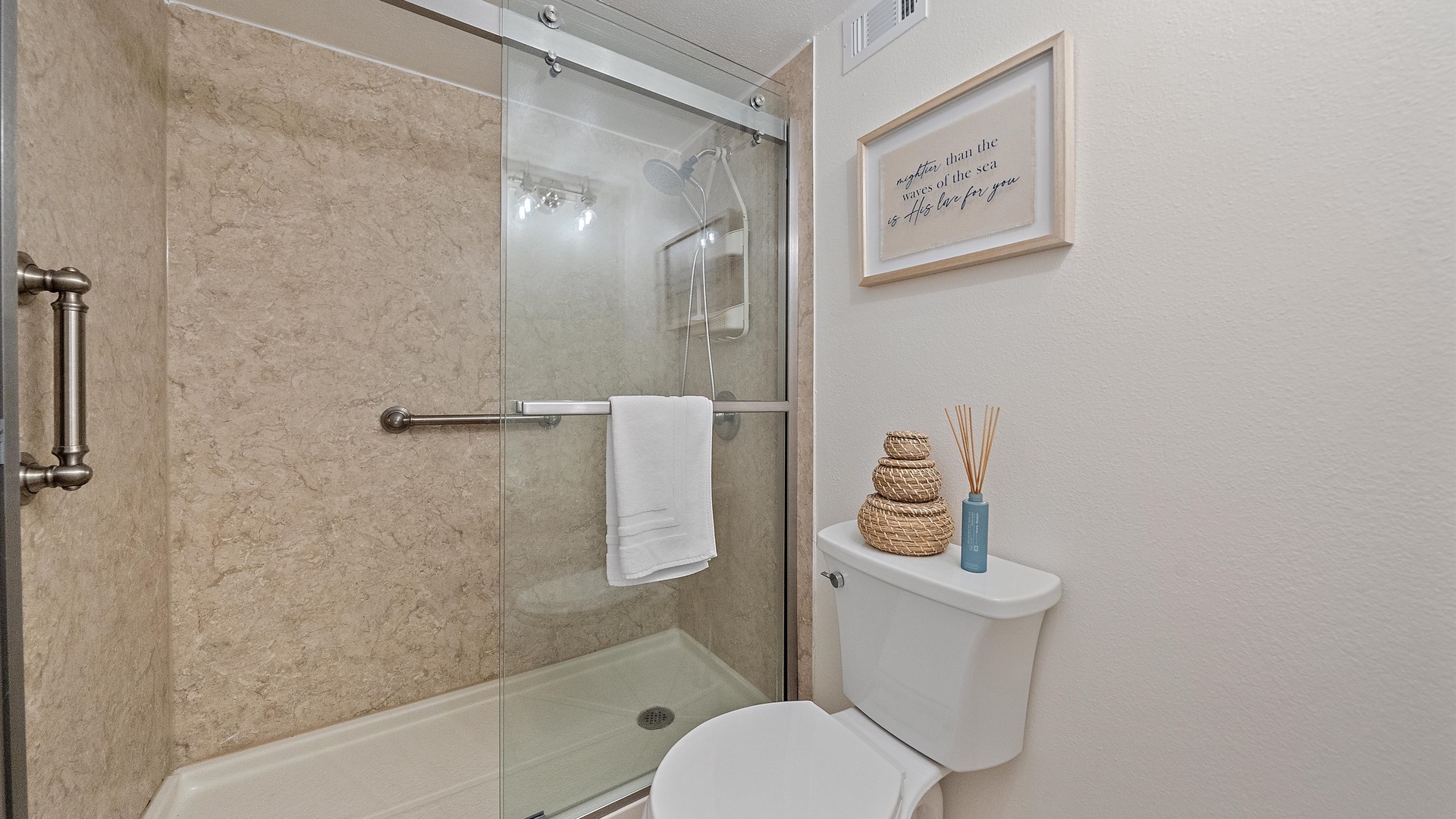 Step into your stylish bathroom featuring a spacious walk-in shower with elegant glass doors, fresh towels, and thoughtful coastal touches that make you feel right at home.