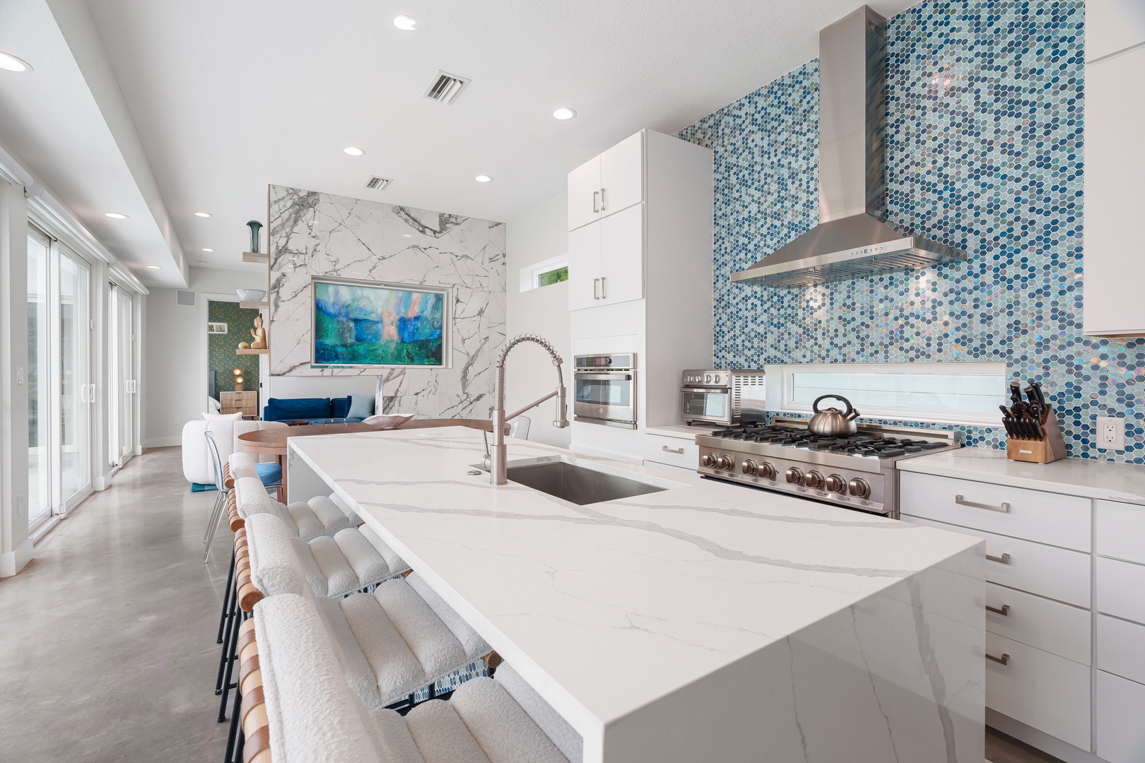 Gather around the spacious marble island where stunning blue mosaic tiles and modern appliances set the stage for memorable meals together in this bright, stylish kitchen.