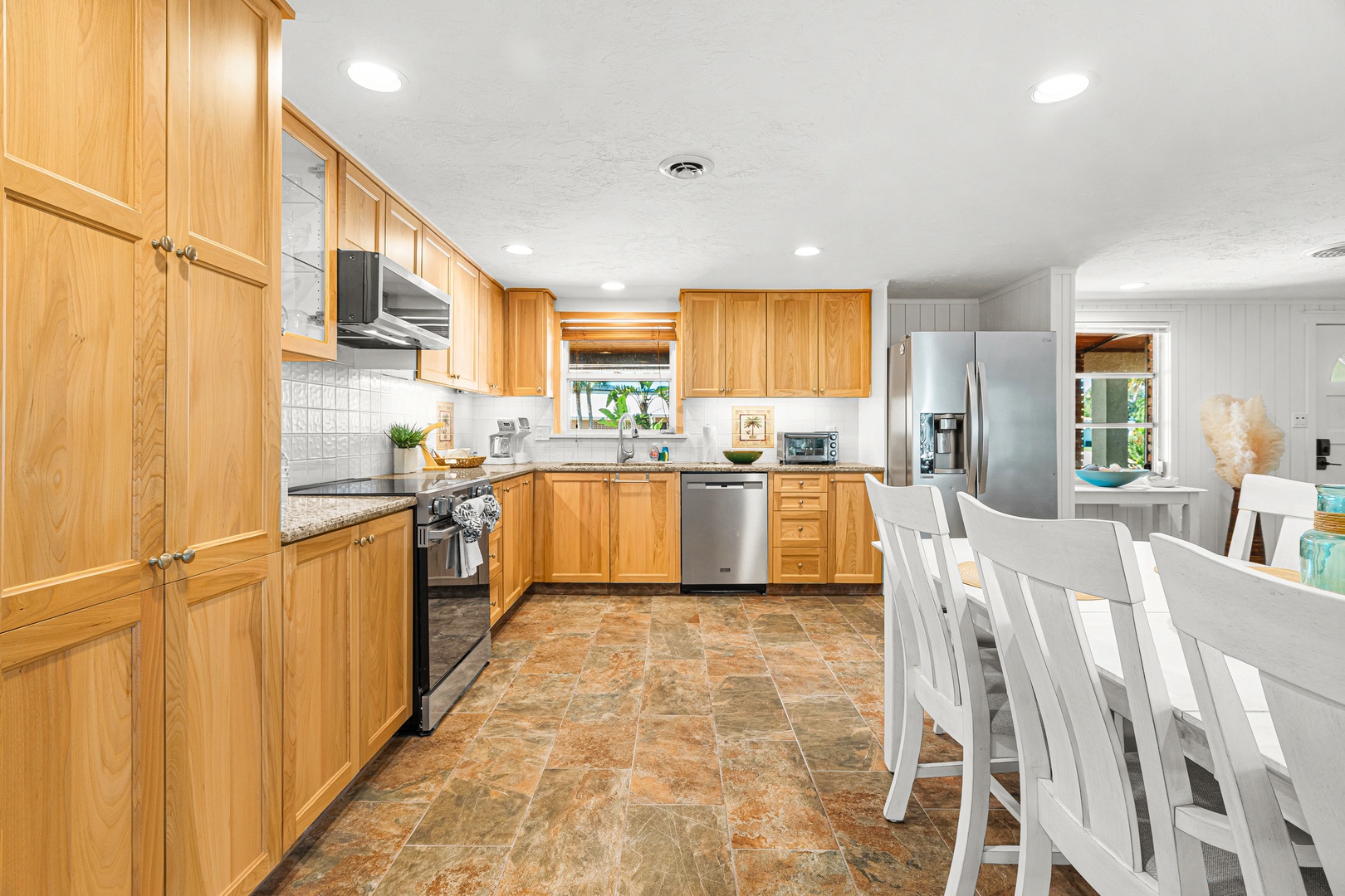 Gather around the sleek dining table in your spacious, sunlit kitchen where warm wood cabinetry and modern stainless appliances invite effortless meal prep and memorable conversations.