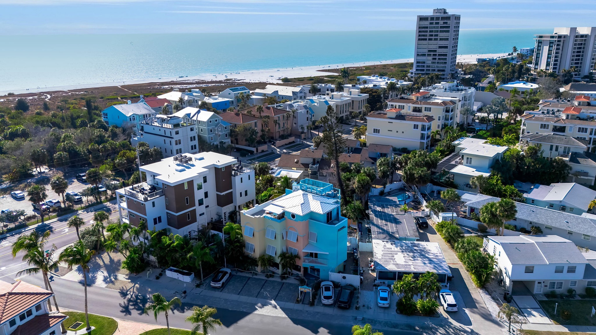 Aerial view of the property and surrounding beachfront neighborhood, showcasing the coastal setting and proximity to the sandy shoreline.