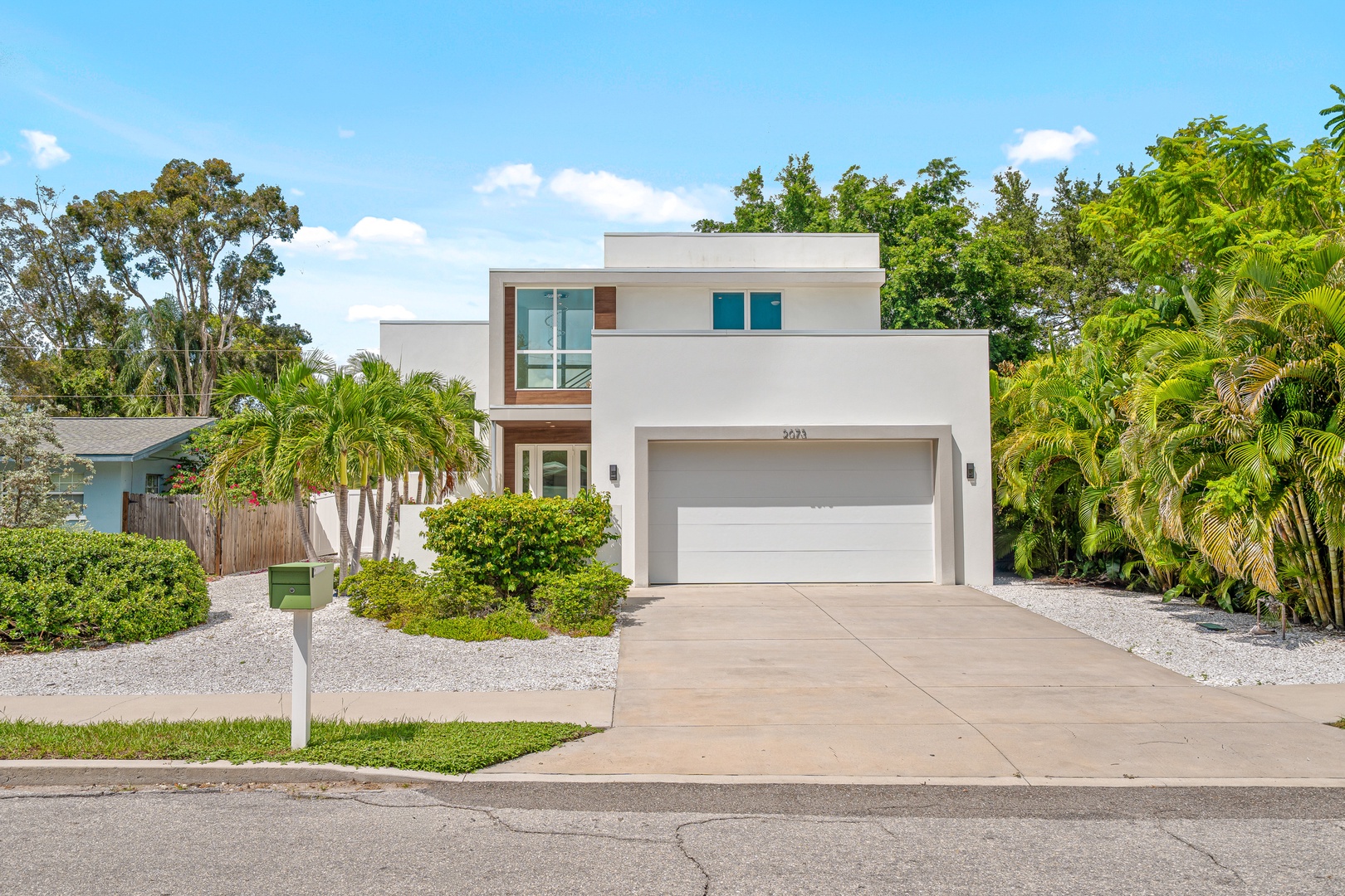 Modern tropical retreat with sleek architecture nestled among lush greenery and swaying palms, offering a private oasis in a peaceful neighborhood setting.