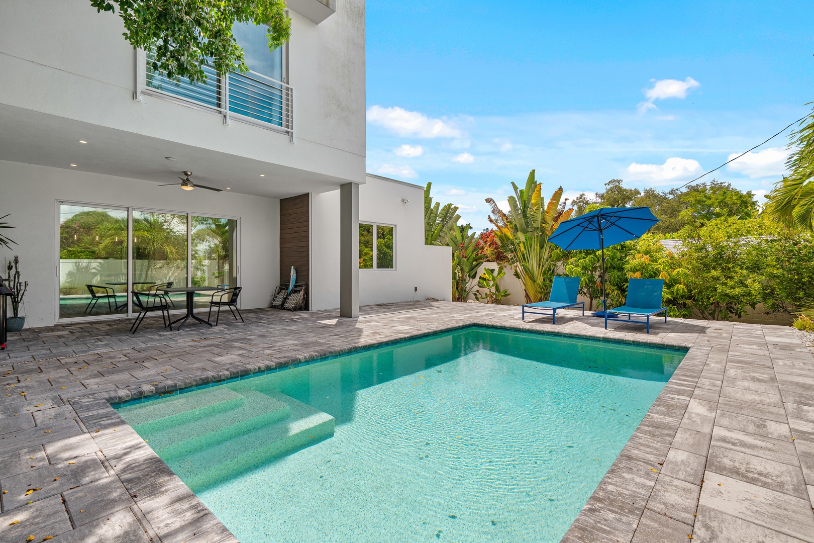 Dive into your private oasis, where crystal-clear waters invite you to cool off under vibrant blue skies. Lounge poolside with lush tropical greenery framing your sunny escape.