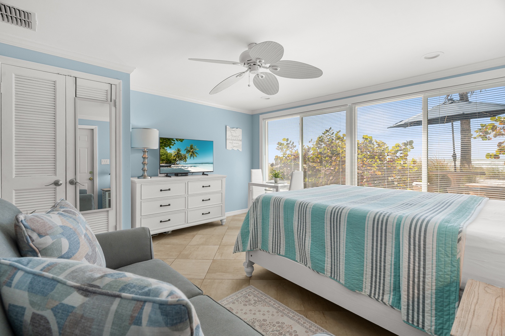Wake up in this serene coastal bedroom where soft blue hues and tropical touches create your perfect seaside retreat.