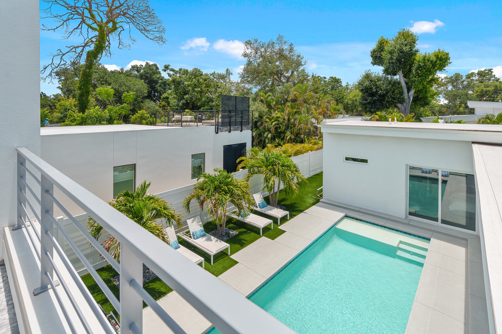 Modern vacation home with private pool and courtyard, surrounded by lush mature trees and contemporary architecture, set in a peaceful residential area.