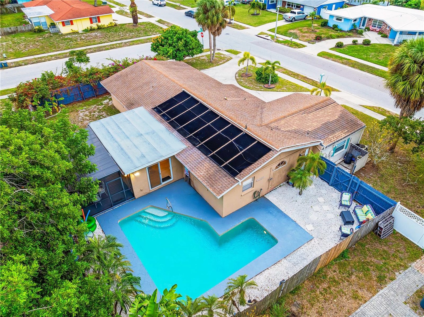 Aerial view of the home with a fenced-in private backyard oasis, heated swimming pool, propane gas grill and seating areas perfect for outdoor dining with friends and families traveling with children or pets.