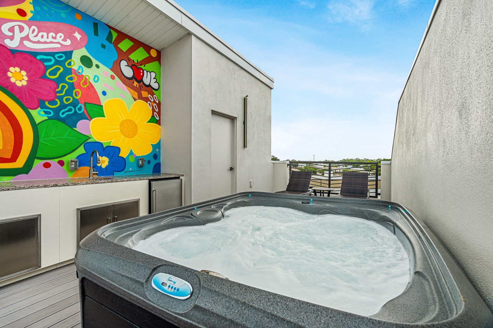 Sink into the bubbling hot tub on your private rooftop deck, surrounded by vibrant murals and open sky—your perfect escape after a day of adventure.