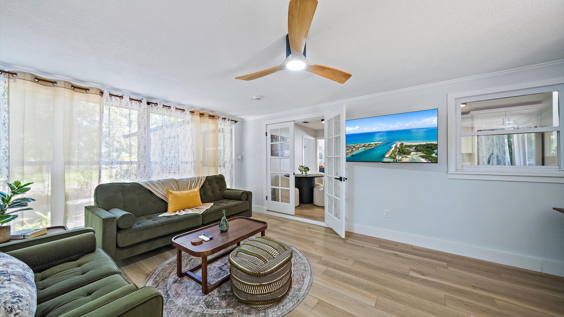 Relax on plush sofas in your bright, open living room, where soft breezes drift through sheer curtains and warm wood accents create a welcoming retreat after a day exploring.