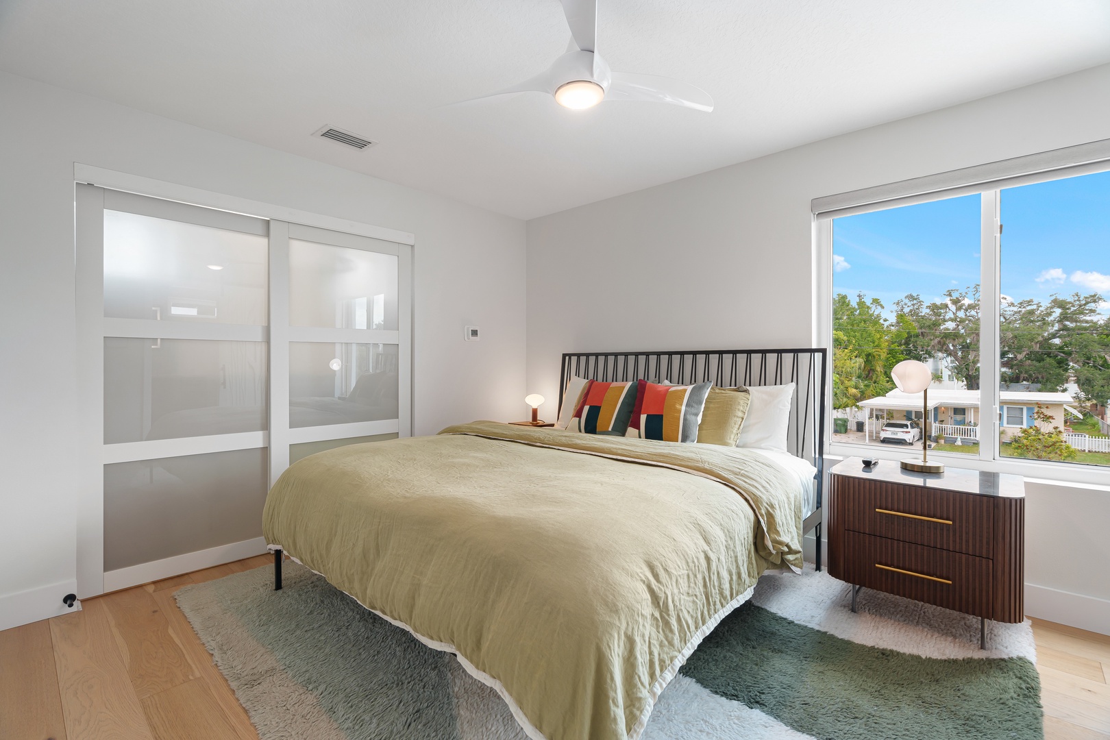 Drift off in your bright, modern bedroom with fresh breezes from the ceiling fan and sunlight streaming through large windows framing peaceful neighborhood views.