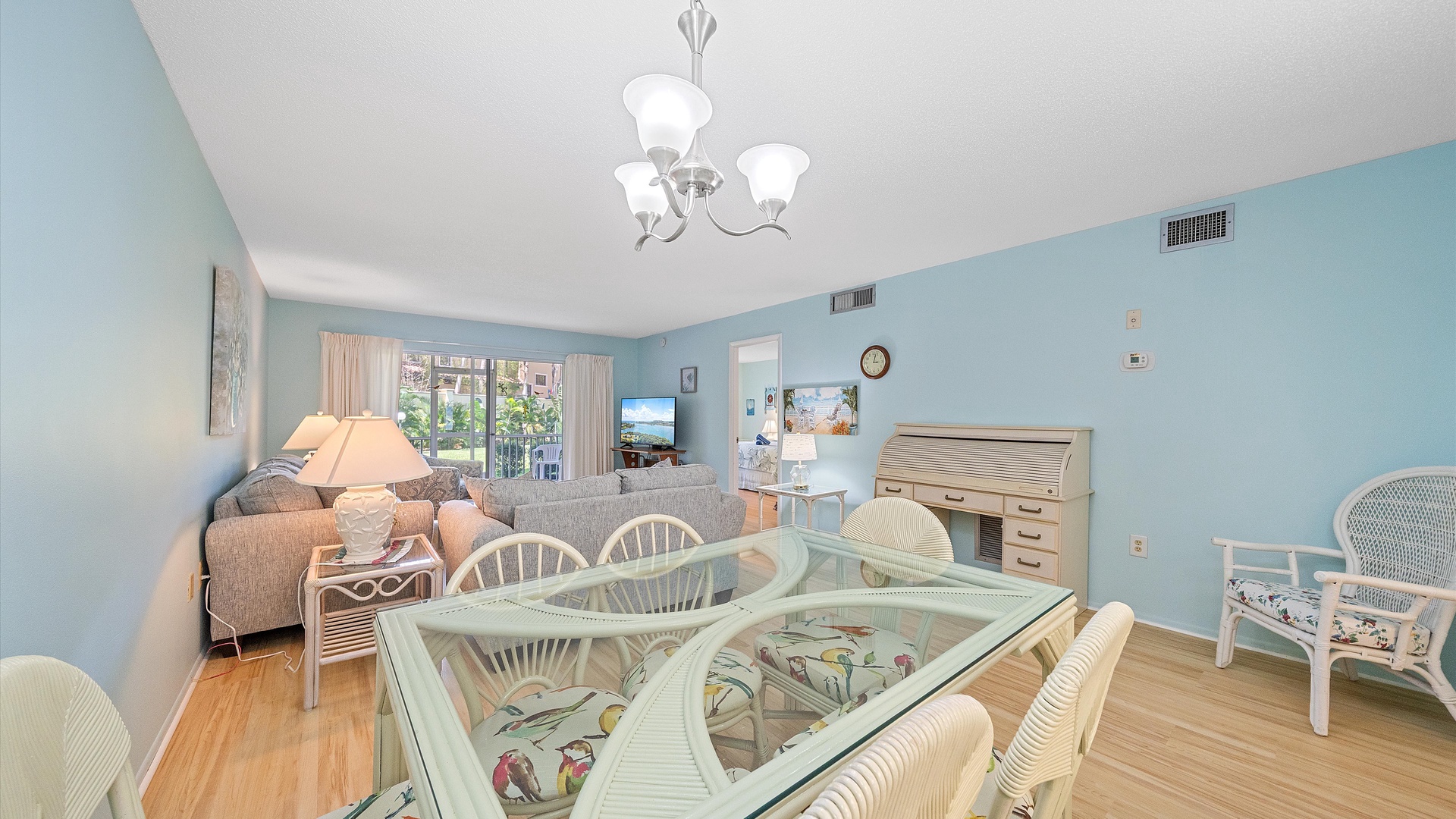 Relax in your spacious living and dining area, where coastal-inspired decor, soft blue walls, and natural light create a soothing retreat. Gather around the elegant glass table or unwind on plush seating after beach days.