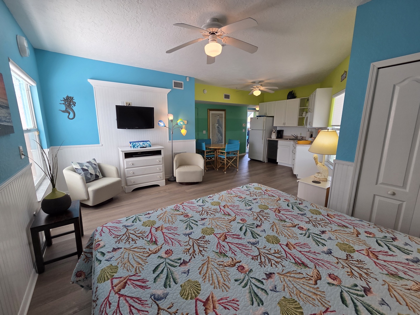 Settle into your cheerful coastal studio where vibrant turquoise walls and tropical-themed linens invite you to unwind. A full kitchen lets you prepare meals at your leisure, while comfortable seating and entertainment await after sunny beach days.