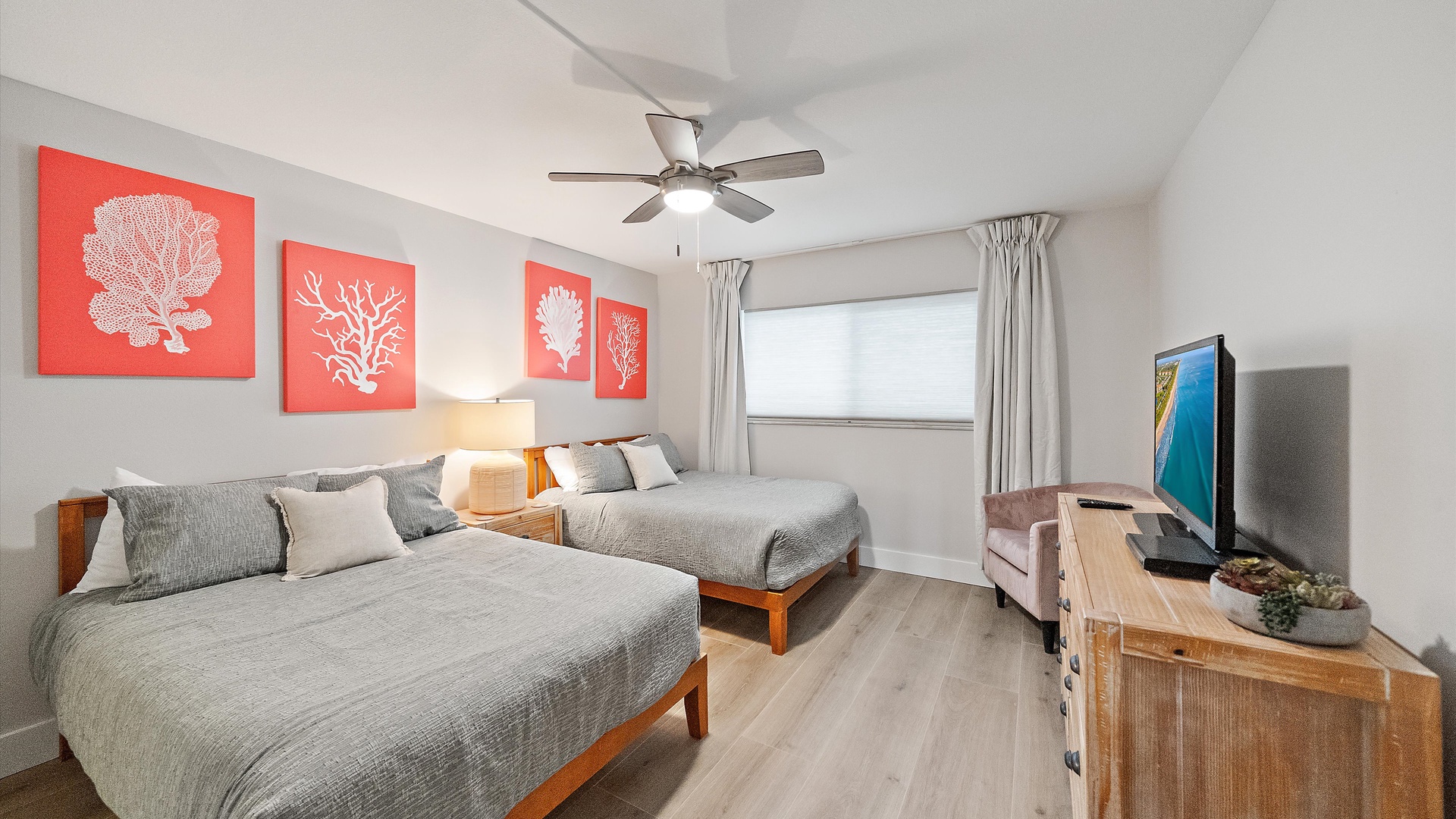 Rest peacefully in your coastal-themed bedroom with twin beds, cheerful coral artwork, and a cozy seating area for relaxing.