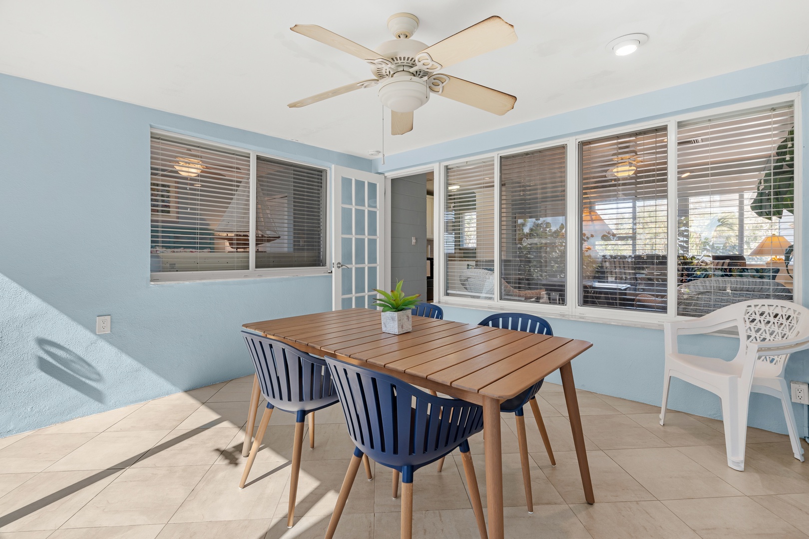 Enjoy meals in your bright sunroom with corner windows, wood table, and cooling ceiling fan creating the perfect dining retreat.