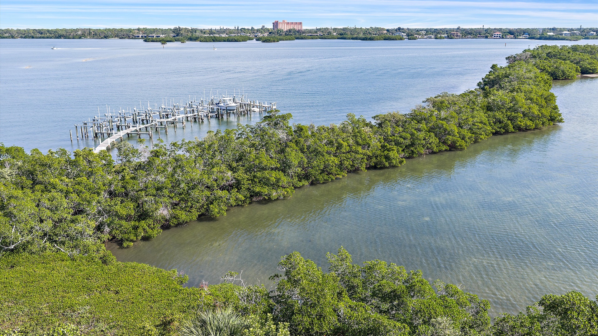 Aerial view of pristine waterfront with marina docks and lush mangrove islands creating a peaceful coastal setting.
