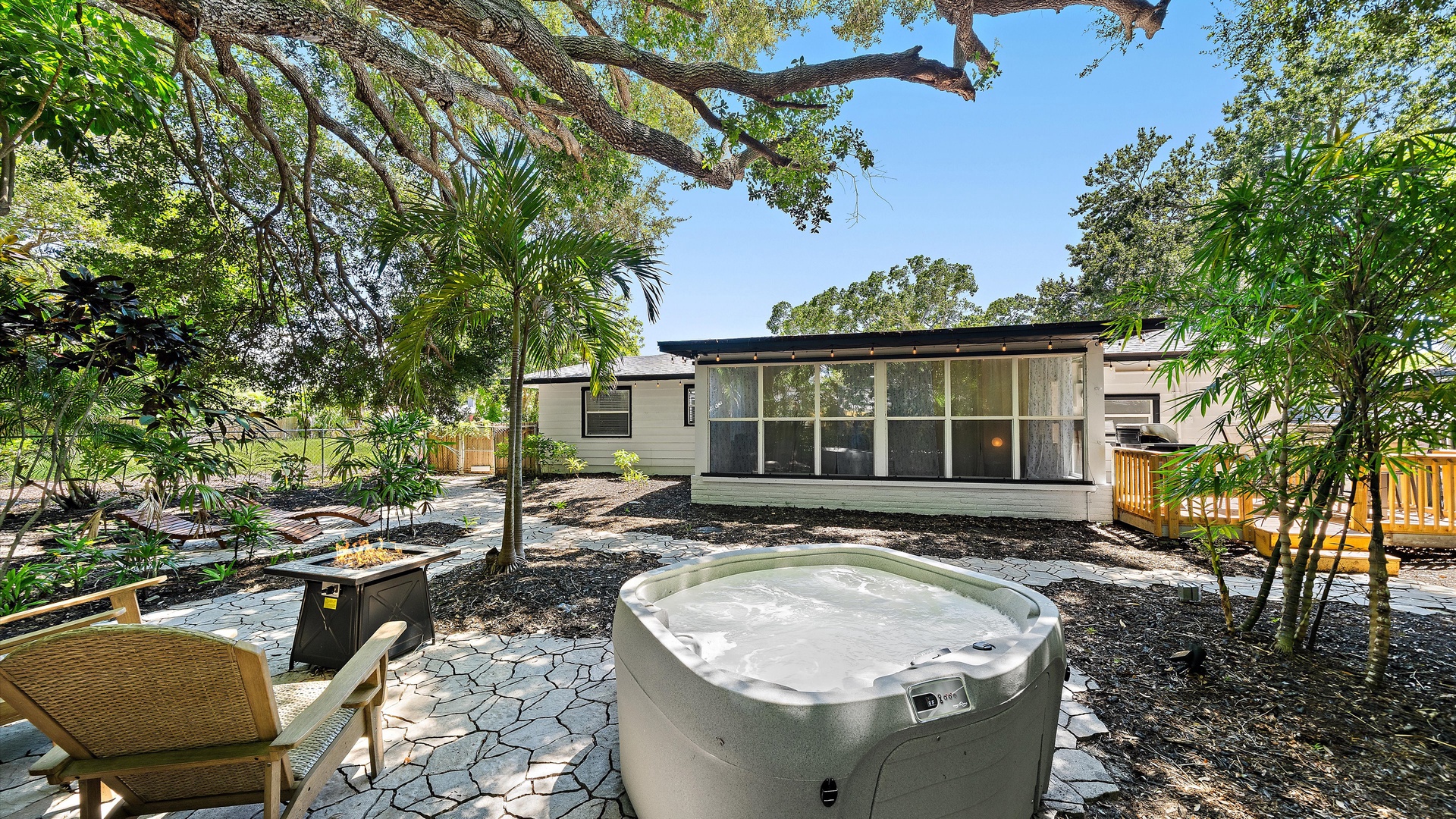 The property features a peaceful outdoor retreat surrounded by lush greenery and natural landscaping, with a secluded hot tub for relaxation and a tranquil setting under mature trees.